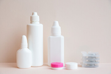 Contact lenses and lens care products on light pink background