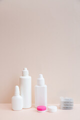 Contact lenses and lens care products on light pink background