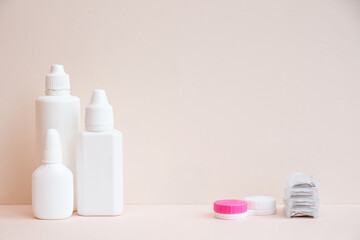 Contact lenses and lens care products on light pink background