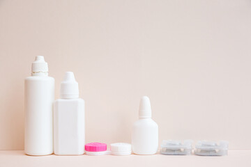 Contact lenses and lens care products on light pink background