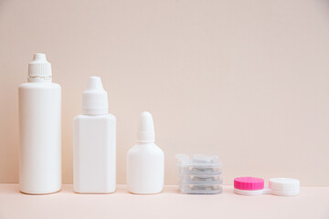 Contact lenses and lens care products on light pink background