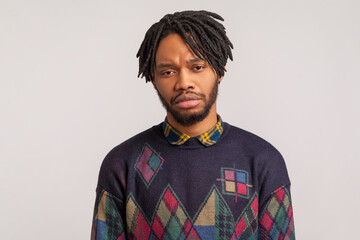Upset frustrated bearded guy with dreadlocks looking at camera with sadness and depression, bad day, racism. Indoor studio shot isolated on gray background
