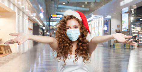 Happy woman Santa in protective medical mask having fun in mall. Open shopping and Christmas sale concept