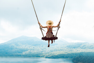 Beautiful girl enjoying freedom on swing in Bali, Indonesia - obrazy, fototapety, plakaty