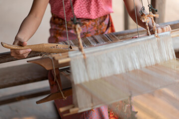 Close-up of women's hands weaving with traditional Thai weaving machine