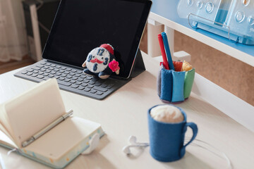 Toy felt handmade cute alarm clock against the background of a white sheet, opened book, tablet . Concept of online, homeschooling, back to school. Copy space.