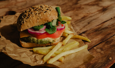 Healthy vegan spinach, tomato, arugula, onion and cheese green burger with potatoes 