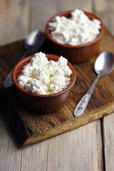 Selective focus. Fresh granular cottage cheese in bowls. Rustic style.