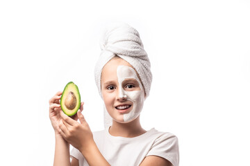 10 years old preteen chilling making clay facial mask and holding avocado fruit. Teenage girl doing anti blemish skin treatment. concept of natural cosmetics for young skin