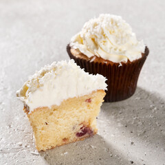sliced blueberry cupcake, muffin, with cream and coconut flakes on gray concrete background