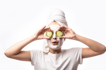 happy child girl in towel with mask on face and cucumber on eyes getting beauty tretment. concept of natural cosmetics for young skin