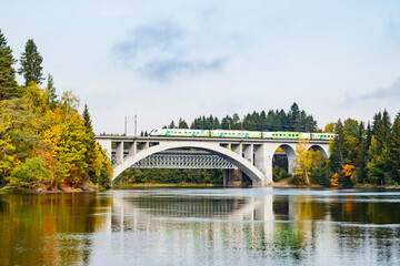 Kouvola, Finland - 25 September, 2019: Autumn landscape of bridge with moving passenger train and Kymijoki river waters in Finland, Kymenlaakso, Kouvola, Koria