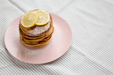 Homemade Lemon Ricotta Pancakes on a pink plate, side view. Space for text.