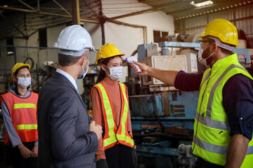 Supervisor use meter to measure temperature degree   of employees or engineer before work in factory, Covid-19 screen and protection, team wear face mask while working in manufacturing 