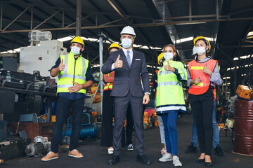 Leader or manager meeting with engineer and technician or operator while posing in factory workplace, team working at maintenance machine shop, face mask covid-19 protection