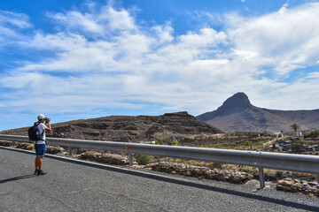 Latin American tourist photographing a mountain landscape.