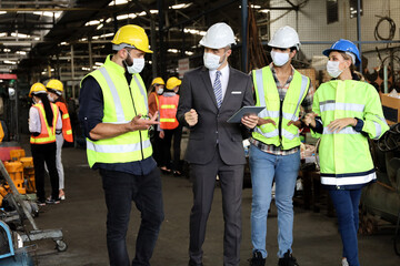 Leader or manager using tablet and meeting with engineer and technician while line walk in factory workplace, team wear face mask whine working at maintenance machine shop 