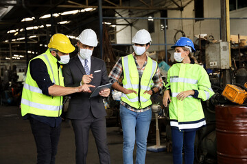 Leader or manager using tablet and meeting with engineer and technician while line walk in factory workplace, team wear face mask whine working at maintenance machine shop 