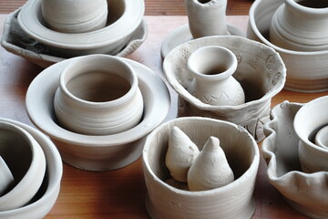 handmade unbacked crockery and pots on the table in the potter's studio. clay before firing in a ceramic kiln