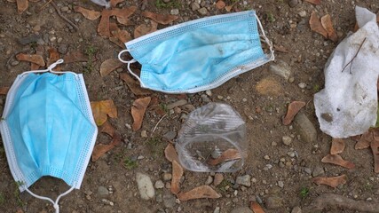 Fototapeta na wymiar 4K, Medical face mask on the floor in the street. Improperly discarding the used surgical masks haphazardly in a bin basket. Lost disposable face mask for protection the coronavirus Covid-19