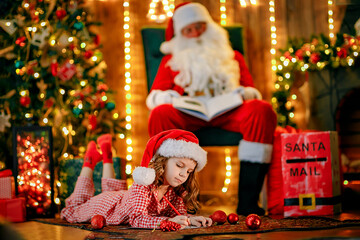 Merry Christmas, santa claus and little child girl at night at the Christmas tree.