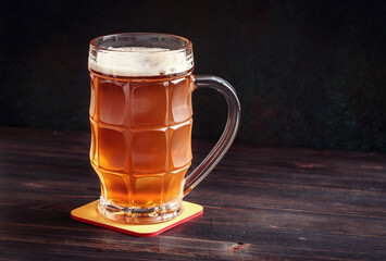 Lager beer mug on wooden table with copy space in dark ambience