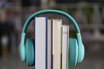soft focus of the books stacked up with headphone on bookshelf background.