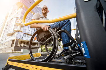 A man in a wheelchair on a lift of a vehicle for people with disabilities