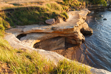 Landscape with lonely sea coast and sandstone cliff, sunset time. Estonia, Europe.