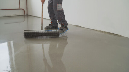 The process of laying the self-leveling floor. Compaction of dry cement-sand mixture. Liquid floor....