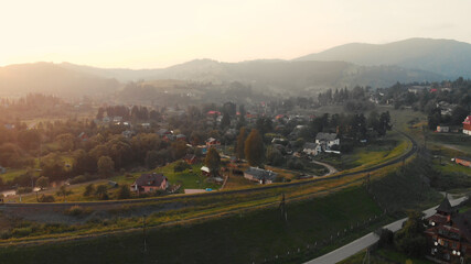 The railroad surrounds the mountain village. Railway is bending the field with beautiful houses.