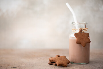 chocolate milkshake in glass bottle with gingerbread crumbly cookies