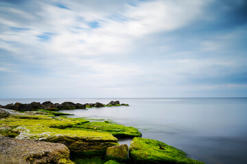 Rocks i shallow water under cloudy sky