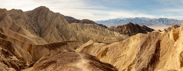 Shades of yellow and brown glitter in the sunlight in a scenery of valleys mountains and ridges,...