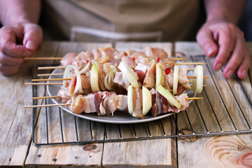 Selective focus. Raw kebabs on wooden sticks are prepared by the chef.