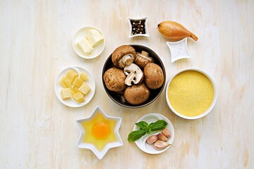 Prepared ingredients for cooking polenta with fried mushrooms and an egg on a light concrete background. Step by step recipes. Polenta and corn grits recipes.
