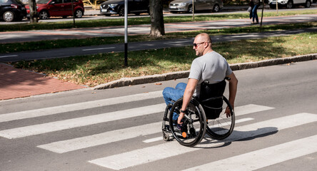 Handicapped man in wheelchair crossing street road
