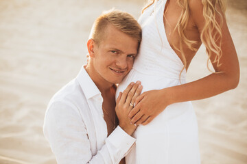 A man kisses his wife's pregnant belly.