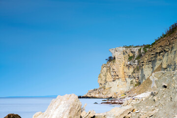 Limestone cliff next to ocean with boulders in foreground