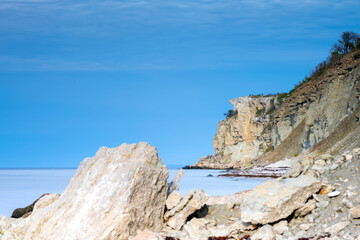 Limestone cliff next to ocean with boulders in foreground