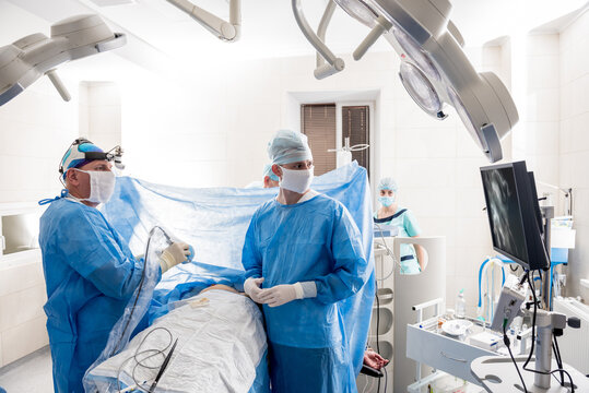 The surgeon uses a portable fluorescence imaging device during breast removal.