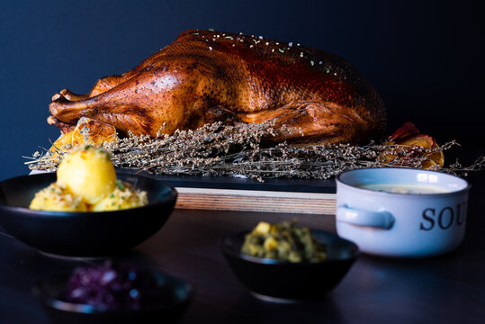 Martinsgans braten mit Garnituren im Vordergrund. Beilagen im Vordergrund erkennbar.