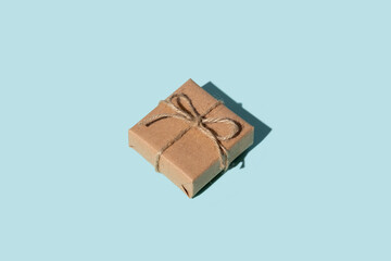 Birthday gift. Long-distance care package. Holiday surprise. Festive congratulation. Present wrapped in vintage rustic beige paper box isolated on blue empty space background.