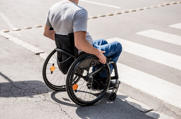 Obraz premium Handicapped man in wheelchair preparing to cross the road on pedestrian crossing