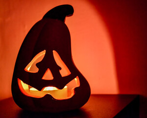 Ceramic Jack O' Lantern candle holder on a table in front of an orange background