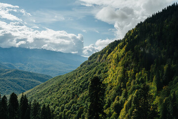 Breathtaking view of a mountain slope covered with forest and massive clouds