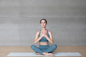 Keuken spatwand met foto Woman practising yoga at home, lotus position on fitness mat. Balance and harmony. © BestForYou