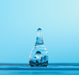 Water drop falling down. Abstract blue background.