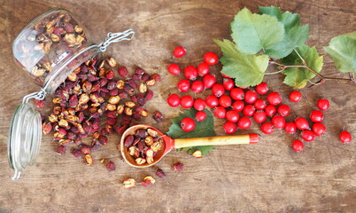 Bright berries of fresh and dried hawthorn on a wooden background. Alternative traditional medicine using hawthorn.