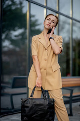 Adult Caucasian Confident Young Business Woman is Talking on Phone Outside near Modern Office Building